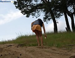 Naughty brunette pisses into a sandpit in forest